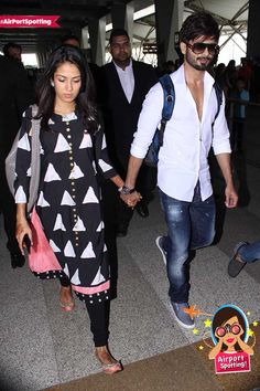 the man and woman are holding hands as they walk through an airport