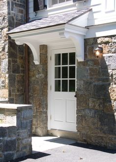 a white door and window in front of a stone building