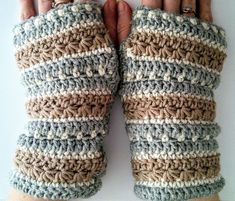 a pair of crocheted fingerless gloves is shown in front of a person's hand