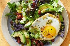 an egg and avocado salad on a white plate next to a bowl of dressing