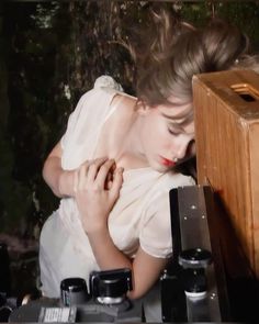 a woman leaning against a wooden box with her eyes closed