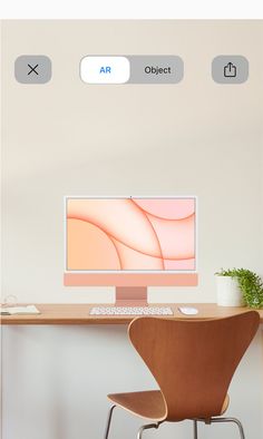 a computer monitor sitting on top of a wooden desk next to a chair and potted plant