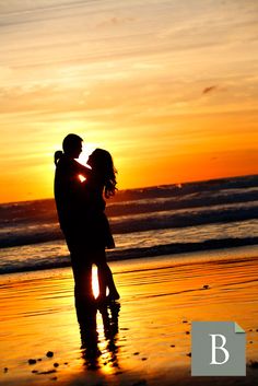 a couple kissing on the beach at sunset