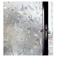 a glass door with flowers and leaves etched on the frosted glass, in front of a living room window