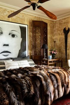 a bedroom with a painting on the wall and a fur bed spread in front of it