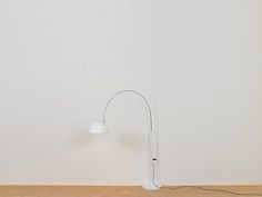 a white table lamp sitting on top of a wooden floor next to a white wall