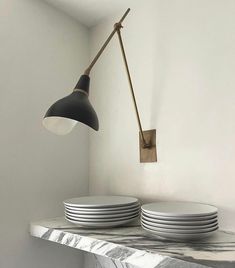 two plates are stacked on top of each other in front of a wall light that is hanging from the ceiling