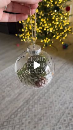 someone holding up a christmas ornament with the words home is where you are