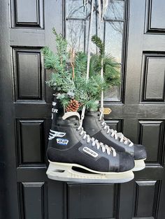 a pair of ice skates are hanging from a door with pine cones and evergreen branches