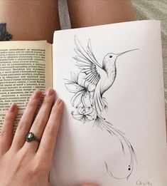 a woman is holding an open book with drawings on it and her hands are resting on the pages