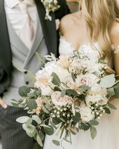 the bride and groom are holding their bouquets in their hands while they stand close together