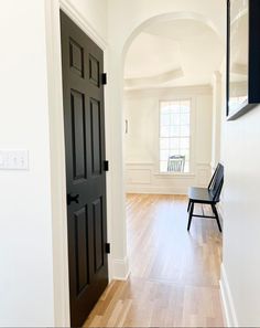 an empty room with a black door and chair