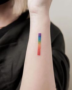 a woman's arm with a rainbow colored tattoo on the left side of her arm