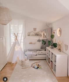 a white bedroom with a teepee tent in the corner and toys on the floor