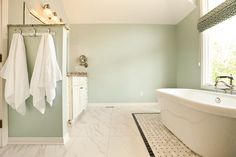 a bath room with a tub a sink and two towels hanging on the rack in front of it