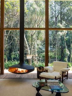 a living room with large windows and a fire place in the middle of the room