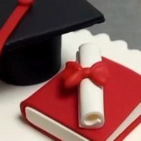 a graduation cap and diploma laying on top of a red book with a white ribbon