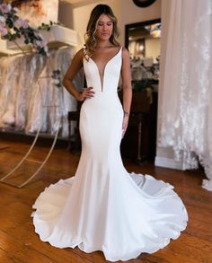 a woman in a white wedding dress standing on a wooden floor with her hands on her hips