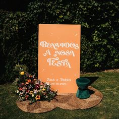 an orange sign sitting on top of a grass covered field next to a bouquet of flowers