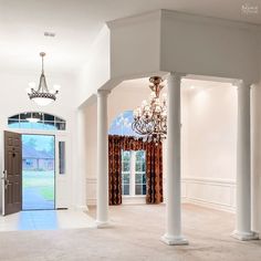 an empty room with columns and chandelier