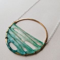 a necklace with a circular pendant hanging from it's side on a white surface