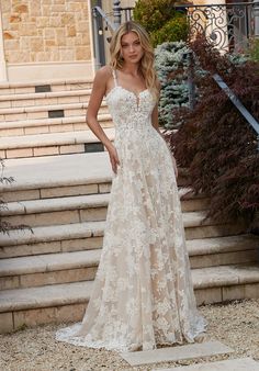 a woman standing in front of some steps wearing a wedding dress with flowers on it