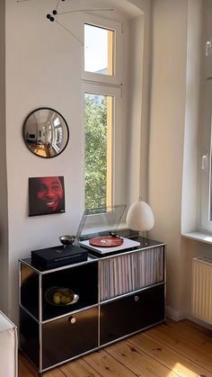 a record player sitting on top of a black cabinet next to a mirror and window