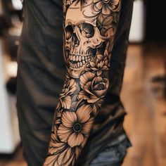 a man's arm with flowers and a skull on the left side of his arm