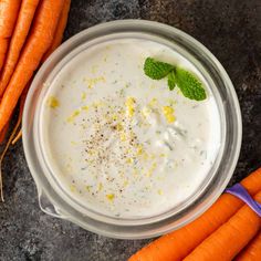 some carrots are next to a bowl of yogurt with mint on top