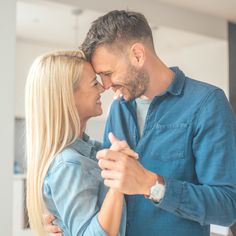 a man and woman dancing together in the living room with their arms around each other