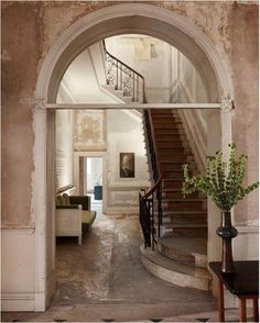 an arched doorway leading to a living room with stairs and couches in the background