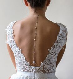 the back of a woman's wedding dress with pearls and beads on her neck