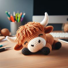 a crocheted cow laying on top of a wooden desk