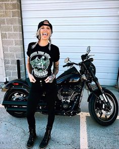 a woman sitting on top of a motorcycle in front of a garage with her mouth open