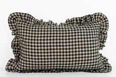 a black and white checkered pillow with ruffles on the front, against a white background