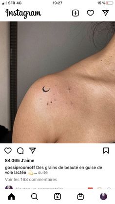 the back of a woman's shoulder with a cross and moon tattoo on it