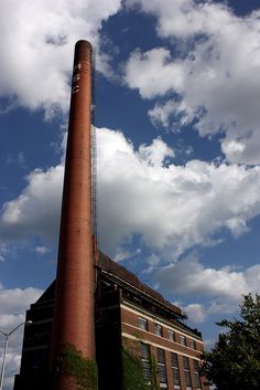 an old brick building with a tall chimney in front of a blue sky filled with clouds