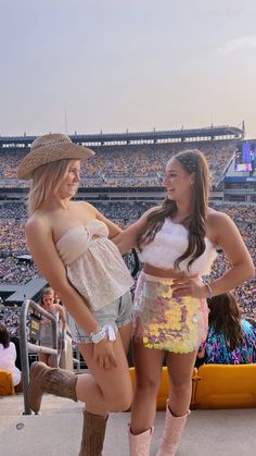 two women standing next to each other in front of a crowd at a football game