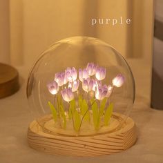 purple flowers in a glass bowl on a wooden stand with the word purple underneath it