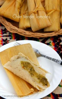 some food is sitting on a white plate and next to a basket full of tamales