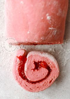 a piece of pink cake next to a slice of strawberry shortbread on a white surface