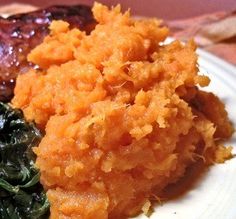 a white plate topped with mashed potatoes, greens and meat on top of it