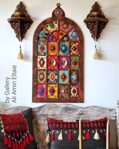 an ornate stained glass window hangs on the wall next to two decorative pillows with tassels