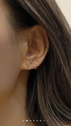 a close up of a woman's ear with three small gold dots on it