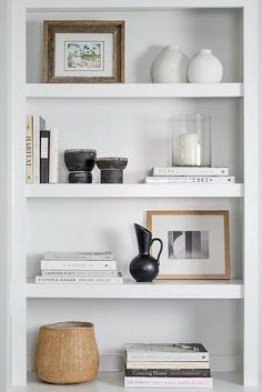 white shelves with books, vases and pictures on them