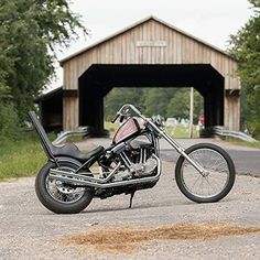 a motorcycle parked in front of a covered bridge