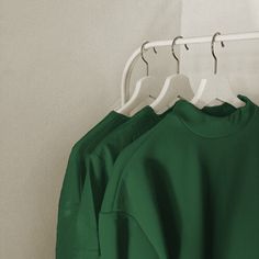 three green shirts hanging on a white hanger