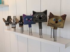 five wooden cats are lined up on a shelf with eyes and mouths painted on them