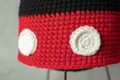 a red and black crocheted hat with two white circles on it's side