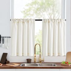 a kitchen sink under a window with white curtains